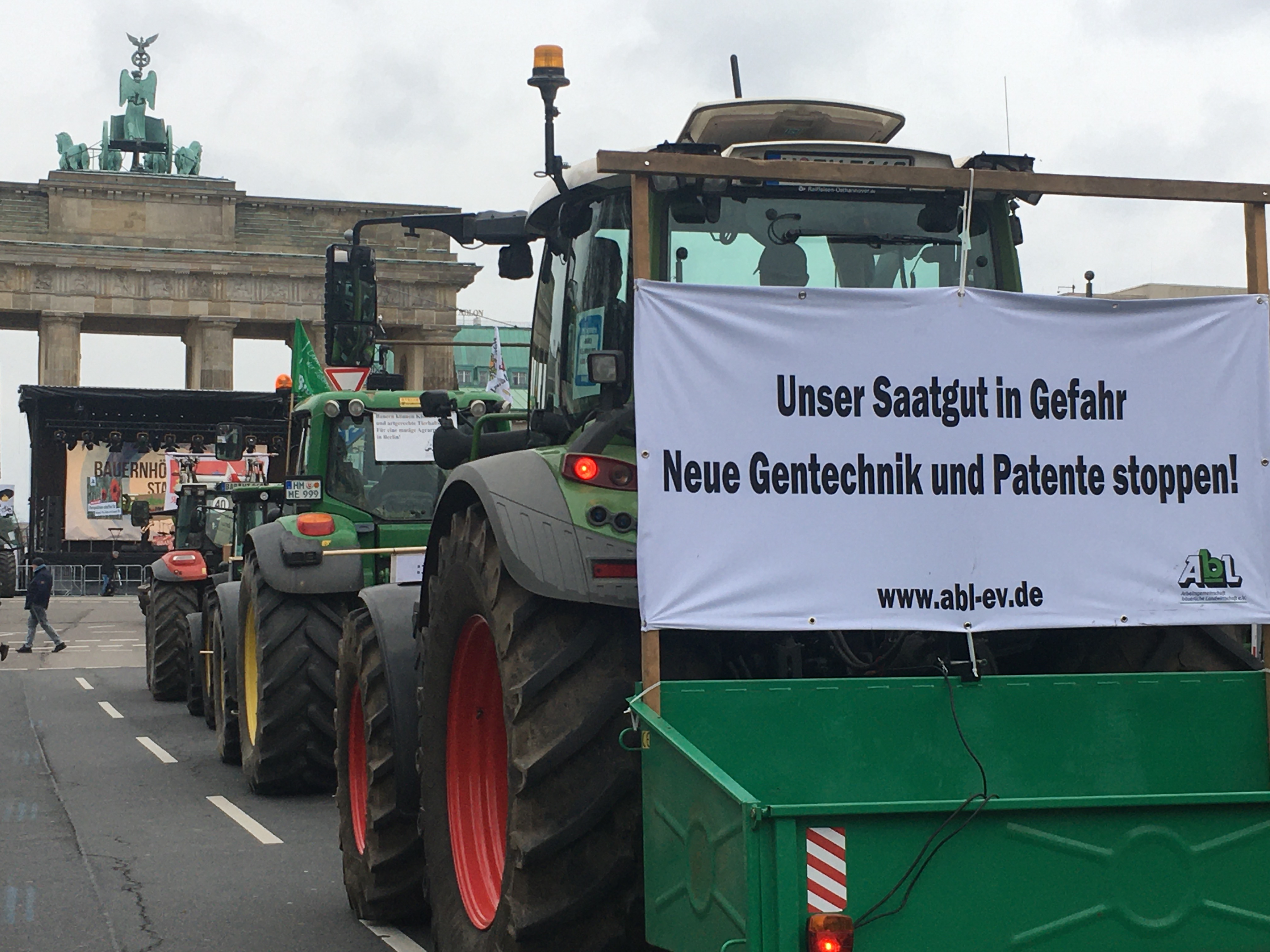 Traktoren mit Bannern vor dem Brandenburger Tor, eines trägt die Aufschrift 'Unser Saatgut in Gefahr - Neue Gentechnik und Patente stoppen'