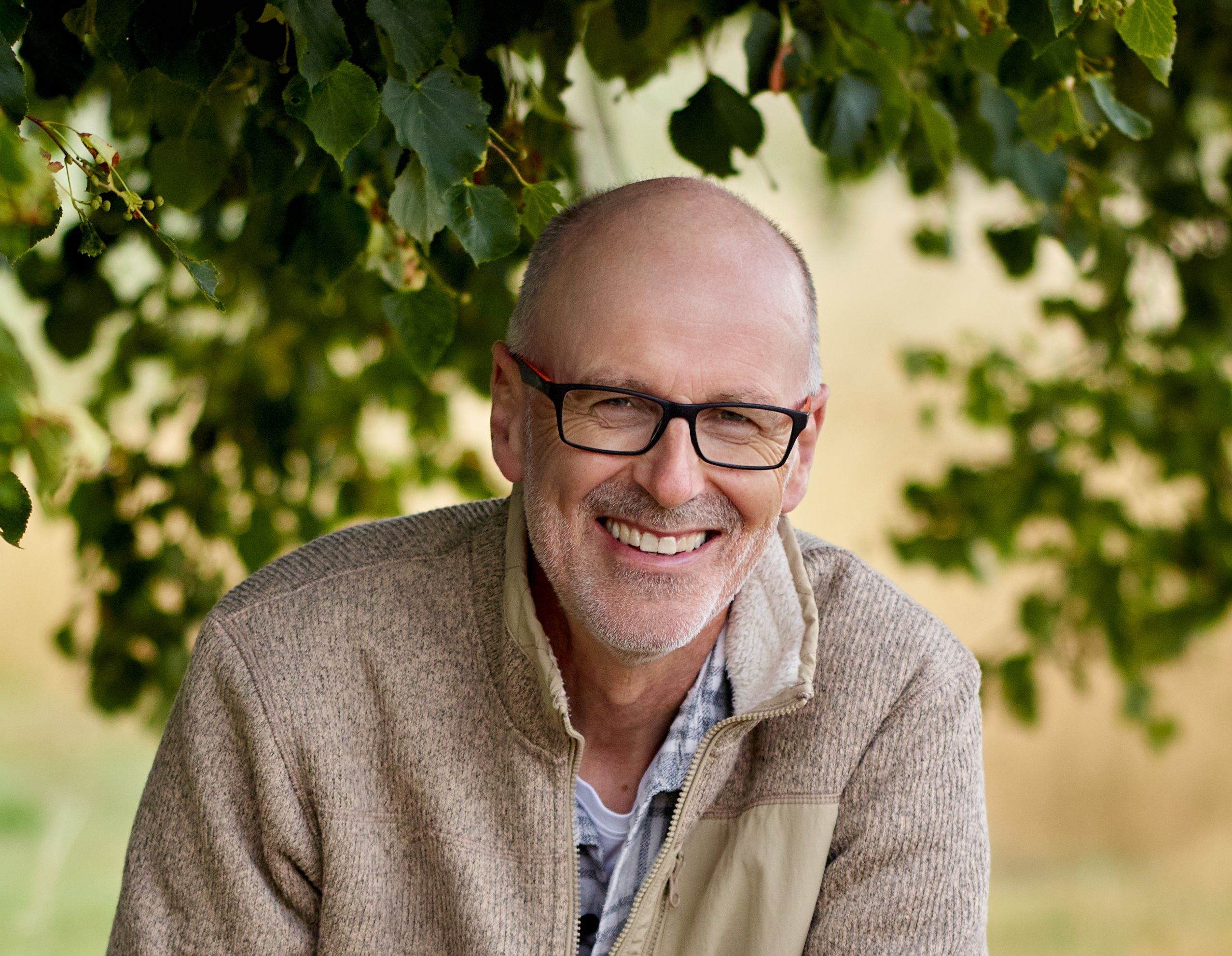 Ein Porträ von Peter Wohlleben. Im Hintergrund sind Äste und Blätter von einem Baum zu erkennen.