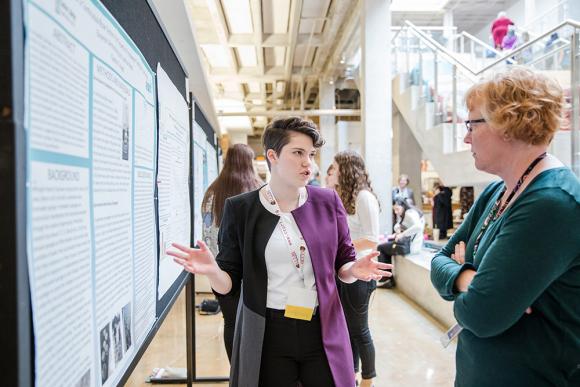 Zwei Frauen diskutieren wissenschaftliche Ergebnisse bei einer Poster-Präsentation.