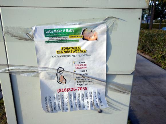 Das Foto zeigt ein mit Klebeband an einem Stromkasten befestigtes DIN-A-4 Blatt mit den Überschriften "Let´s make a baby" und "Surrogate mothers needed". Am unteren Zettelrand befindet sich ein Abreiß-Block mit Kontaktnummer.