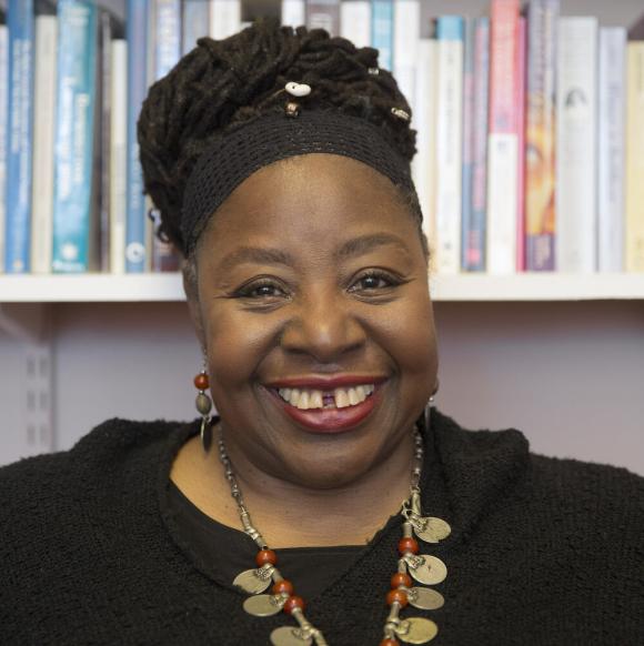 Portraitfoto von Loratta J. Ross. Ihr Gesicht ist vor einem Bücherregal zu sehen und sie lächelt in die Kamera. 