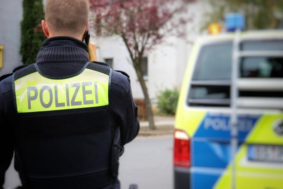 Ein Polizist und ein Polizeibus von hinten